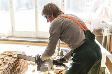 Holzschnitzer in der Werkstatt bei der Bearbeitung von Holz für eine Skulptur mit einer Kettensäge - TCF004939