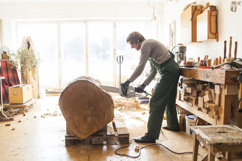 Holzschnitzer in der Werkstatt bei der Bearbeitung von Holz für eine Skulptur mit einer Kettensäge - TCF004940