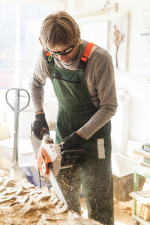 Holzschnitzer in der Werkstatt bei der Bearbeitung von Holz für eine Skulptur mit einer Kettensäge - TCF004941