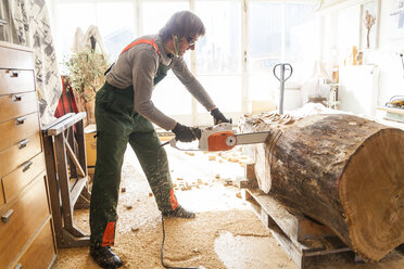 Holzschnitzer in der Werkstatt bei der Bearbeitung von Holz für eine Skulptur mit einer Kettensäge - TCF004944