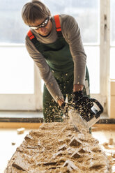 Wood carver in workshopworking on wood for a sculpture with a chainsaw - TCF004949