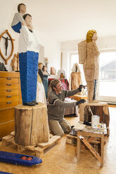 Wood carver in workshop painting his sculpture - TCF004960