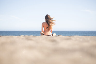 Young blond woman wearing bikini at the beach and looking at