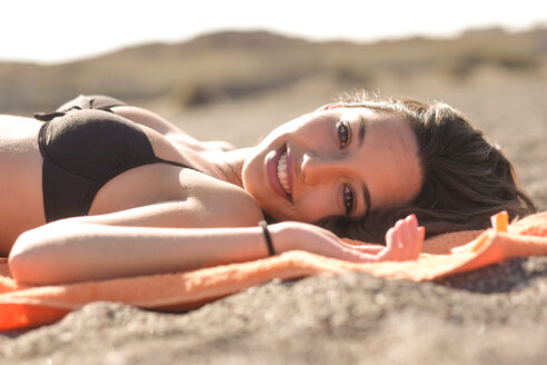 Spanien, Teneriffa, Porträt einer am Strand liegenden jungen Frau - SIPF000338