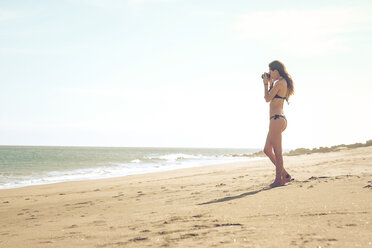Spanien, Teneriffa, junge Frau, die am Strand steht und ein Foto macht - SIPF000342
