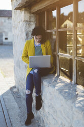 Frau benutzt Laptop vor einem Gebäude - JPF000122