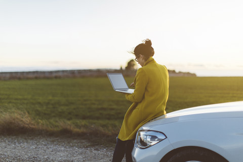 Frau benutzt Laptop im Auto, lizenzfreies Stockfoto