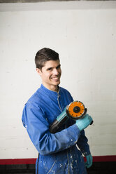 Portrait of smiling construction worker holding an angle grinder - RAEF001024