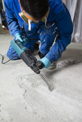 Arbeiter bearbeitet den Zementboden mit einem Presslufthammer - RAEF001030