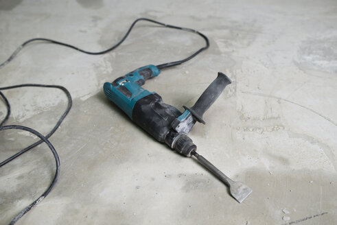 Portable jackhammer lying on cement floor - RAEF001032
