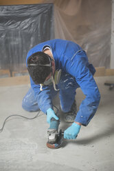 Arbeiter beim Glätten von Zement mit einem Winkelschleifer - RAEF001044