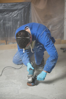 Worker smoothening cement with an angle grinder - RAEF001044