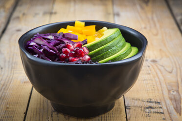 Lunch bowl with black rice, avocado, yellow bell pepper, red cabbage and pomegranate seed on wood - LVF004727