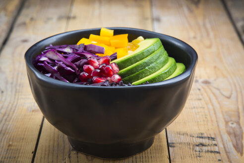 Lunchschale mit schwarzem Reis, Avocado, gelber Paprika, Rotkohl und Granatapfelkernen auf Holz - LVF004727