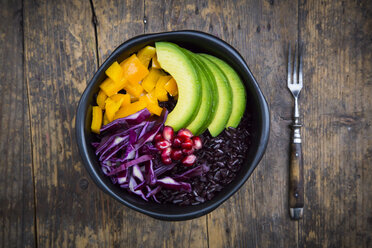 Lunch bowl with black rice, avocado, yellow bell pepper, red cabbage and pomegranate seed on wood - LVF004728