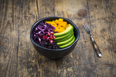 Lunch bowl with black rice, avocado, yellow bell pepper, red cabbage and pomegranate seed on wood - LVF004729