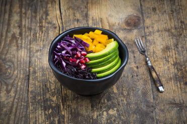 Lunchschale mit schwarzem Reis, Avocado, gelber Paprika, Rotkohl und Granatapfelkernen auf Holz - LVF004729