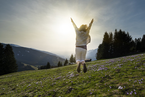 Österreich, Tirol, junge Frau springt auf Alm, lizenzfreies Stockfoto