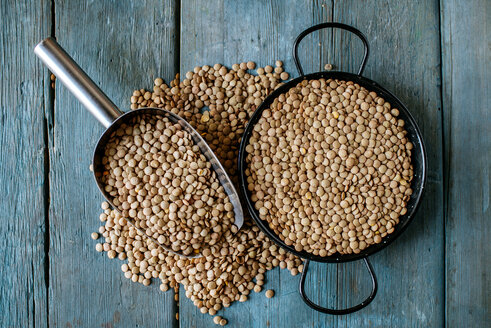 Skillet and metal scoop with dried brown lentils on wood - KIJF000306