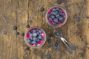 Two glasses of overnight oats with blueberries and berry juice on wood - LVF004735