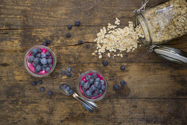 Two glasses of overnight oats with blueberries and berry juice on wood - LVF004737