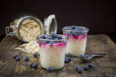 Two glasses of overnight oats with blueberries and berry juice on wood - LVF004738
