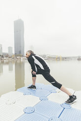 Austria, Vienna, jogger doing stretching exercise on Danube Island - AIF000313