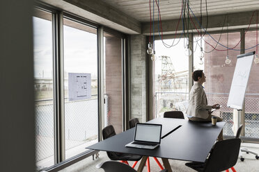 Businesswoman looking at flipchart in conference room - UUF006755