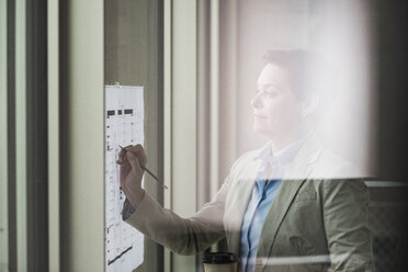 Geschäftsfrau mit Bauplan am Fenster - UUF006766