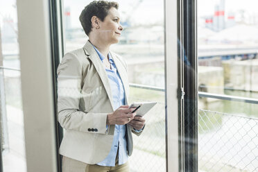 Businesswoman with digital tablet at the window - UUF006777