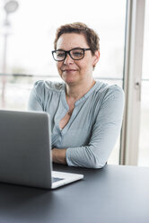 Businesswoman looking at laptop in office - UUF006793