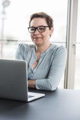 Geschäftsfrau mit Blick auf den Laptop im Büro - UUF006793