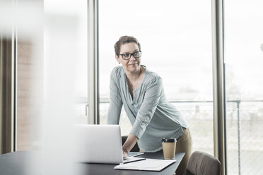 Businesswoman with laptop in office - UUF006796