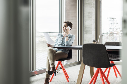 Geschäftsfrau am Mobiltelefon im Konferenzraum, lizenzfreies Stockfoto