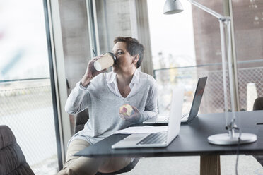 Businesswoman in office drinking coffee - UUF006844