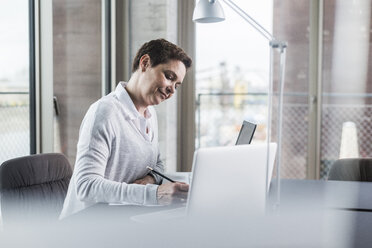 Businesswoman working at desk - UUF006846