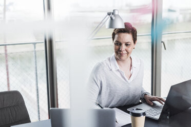 Smiling businesswoman at desk - UUF006847