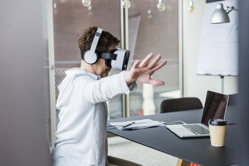 Woman in office wearing virtual reality glasses - UUF006850