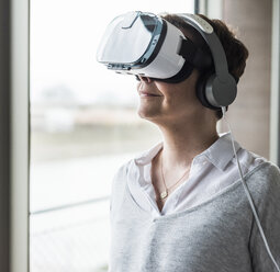 Woman wearing virtual reality glasses and headphones - UUF006851