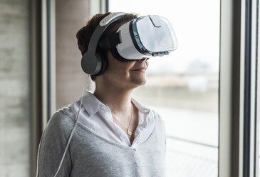 Woman wearing virtual reality glasses and headphones - UUF006852
