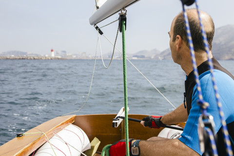Mann segelt mit seinem Segelboot auf dem Meer, lizenzfreies Stockfoto