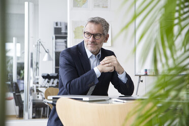 Successful businessman sitting in board room - RBF004271