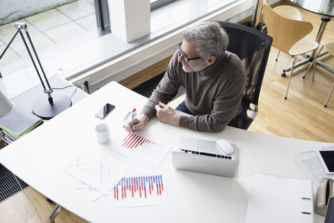 Mature man working in office with charts stock photo