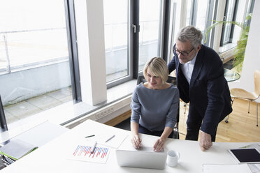 Businessman and woman working together in office using laptop - RBF004276