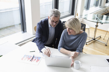 Businessman and woman working together in office using laptop - RBF004277