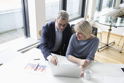 Geschäftsmann und Frau arbeiten zusammen im Büro an einem Laptop - RBF004277