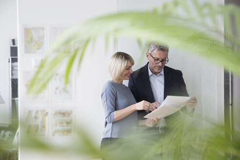 Businessman and woman working together in office discussing documents - RBF004278