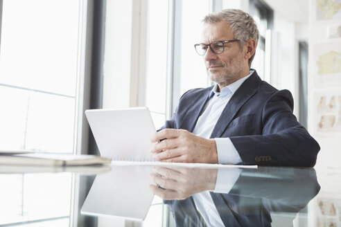 Erfolgreicher Geschäftsmann in seinem Büro mit digitalem Tablet - RBF004299