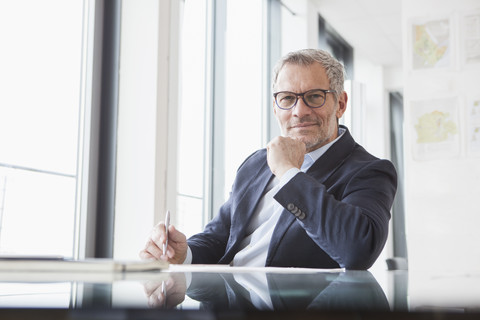 Successful businessman sitting at desk in his office stock photo