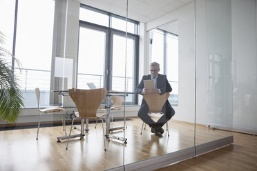 Erfolgreicher Geschäftsmann in seinem Büro mit digitalem Tablet - RBF004312